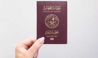 Hand holding Qatar passport close-up